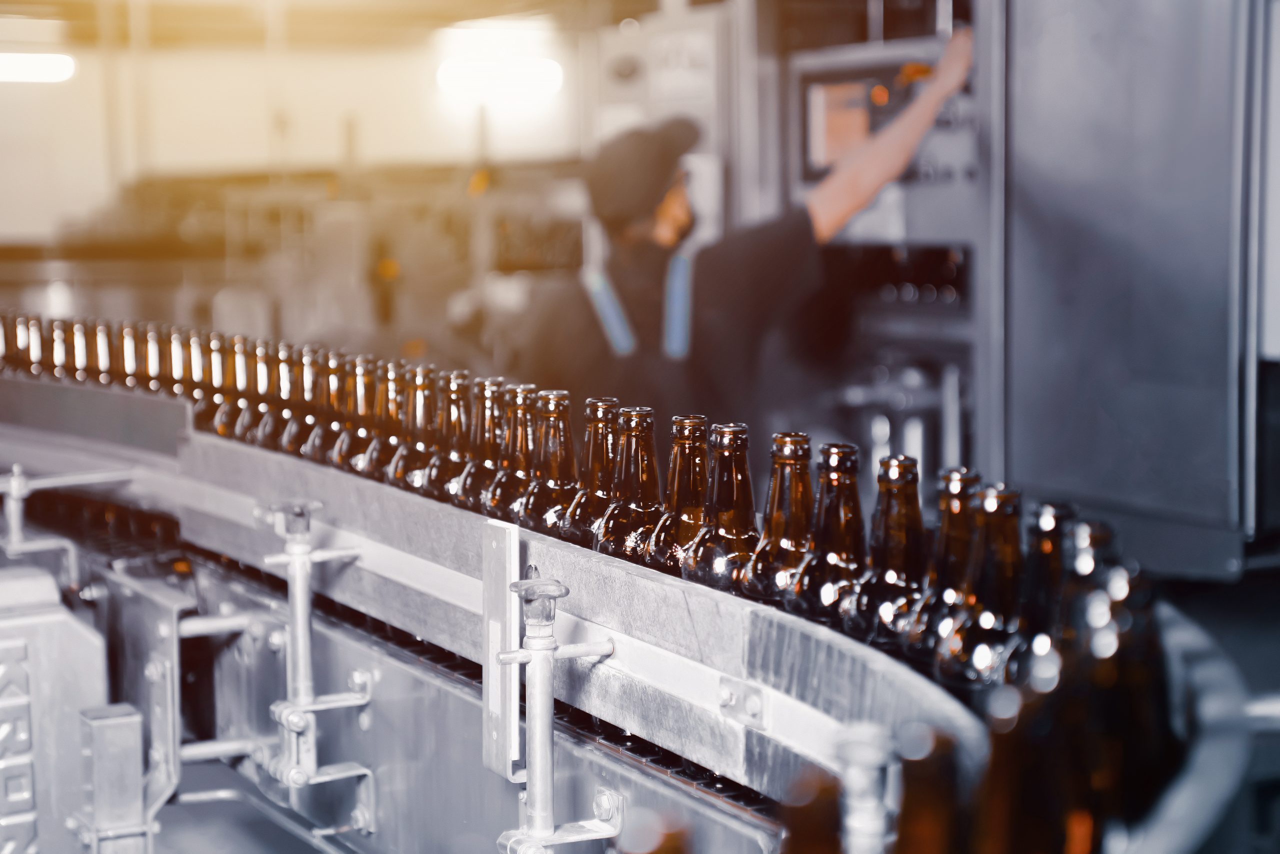 Glass beer bottles of brown color on the conveyor line of beer bottling close up